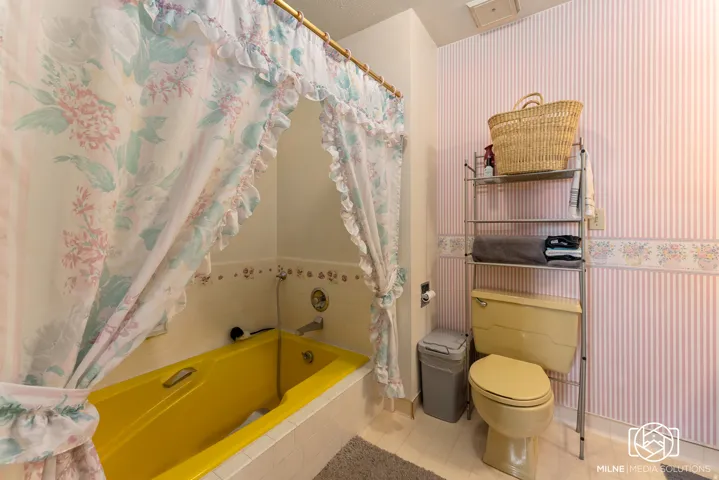 Built-in tub with a yellow finish, chrome fixtures, and white tile surround