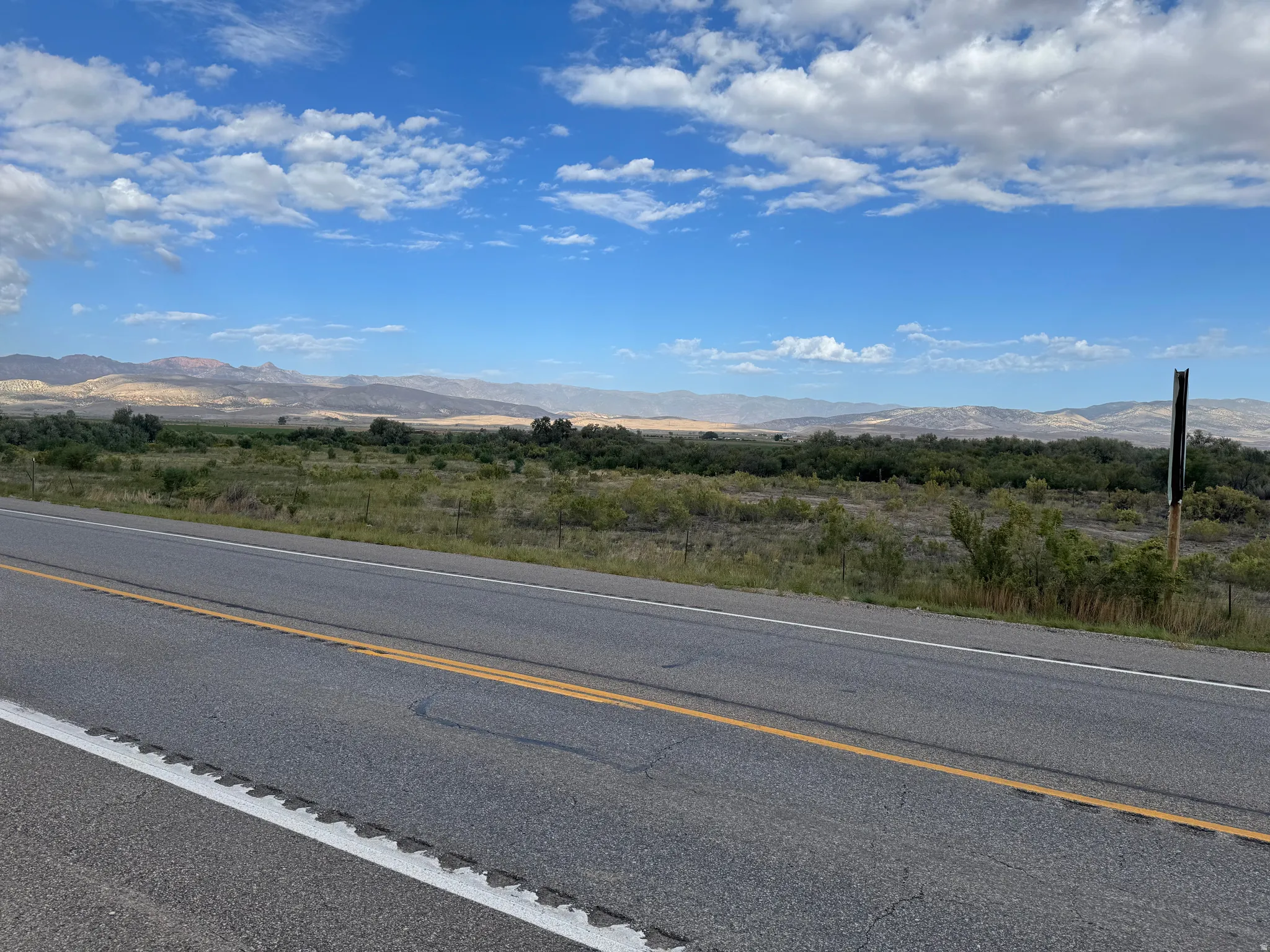 Expansive land parcel with surrounding mountain scenery and a clear sky backdrop