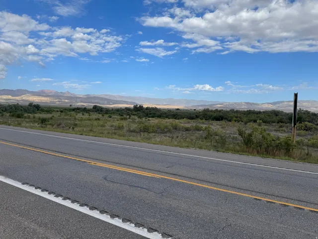 Expansive land parcel with surrounding mountain scenery and a clear sky backdrop