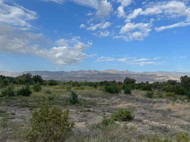 Expansive open terrain with natural vegetation and distant mountain ranges under a blue sky