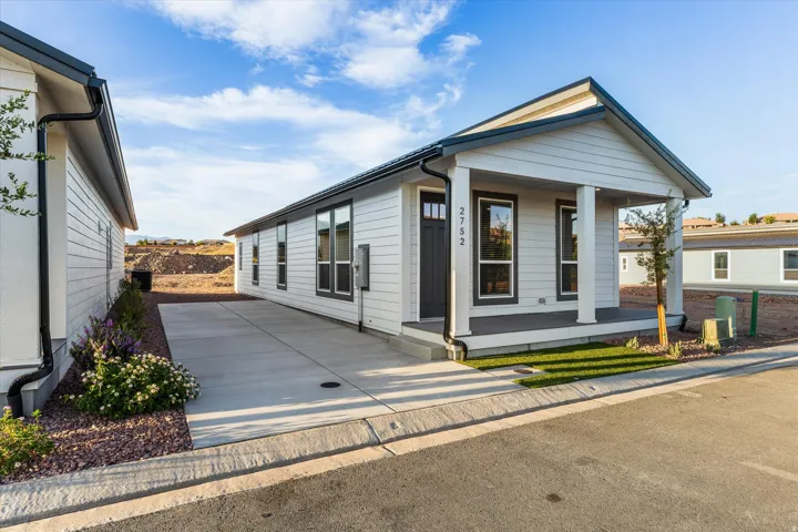 White horizontal siding exterior with a covered front porch featuring two columns, a dark entry door, and a concrete driveway