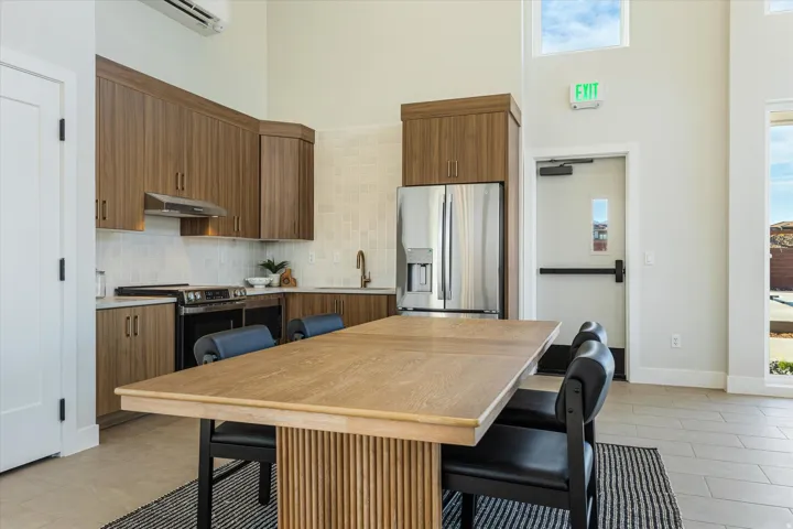 High ceilings with transom windows, wood-finish cabinetry, stainless steel appliances, light-toned tile flooring, and a stone-finish countertop