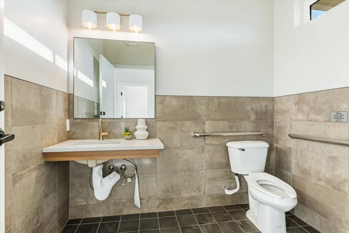Bathroom featuring a floating vanity with a vessel sink, gold-finish faucet, and coordinating wall-mounted light fixture