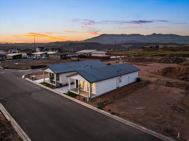 Contemporary new construction featuring a durable metal roof, covered front porches, and a paved street