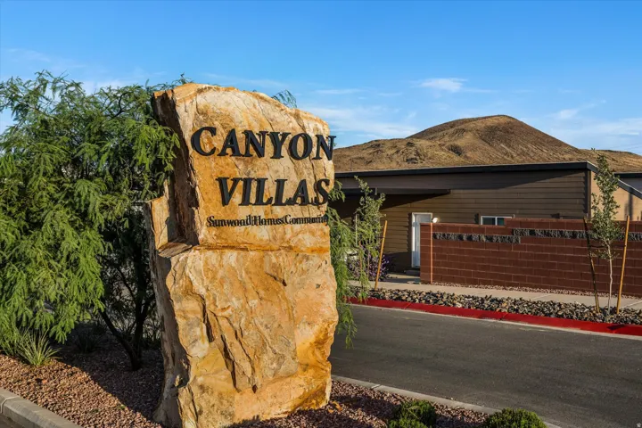 Canyon Villas community entrance sign crafted from natural stone, complemented by desert landscaping and an asphalt roadway