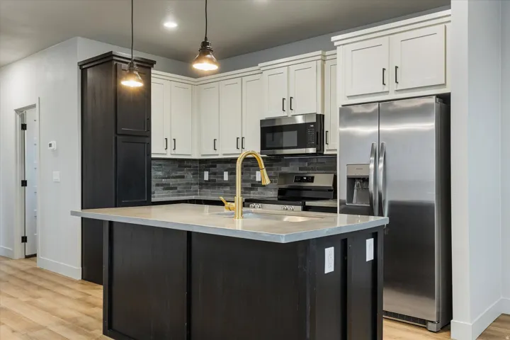 Kitchen featuring a central island with countertop, two-tone cabinetry, stainless steel appliances, and wood-finish flooring