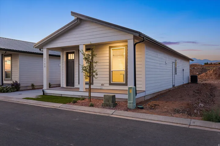 White horizontal siding exterior with a covered porch, dark entry door, and metal roof