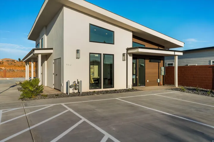 Modern exterior architecture with a sloping roofline, sleek black-framed windows, and a wood-finish accent wall