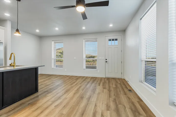 Open-concept living area with wood-finish flooring, a contemporary ceiling fan, and recessed lighting