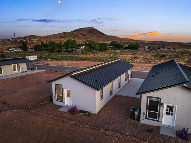 New construction with light-toned siding, dark metal roofing, and a concrete driveway