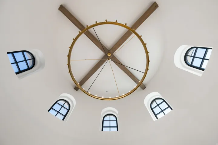 Rotunda ceiling featuring exposed wood beams, a circular chandelier, and arched windows with black mullions
