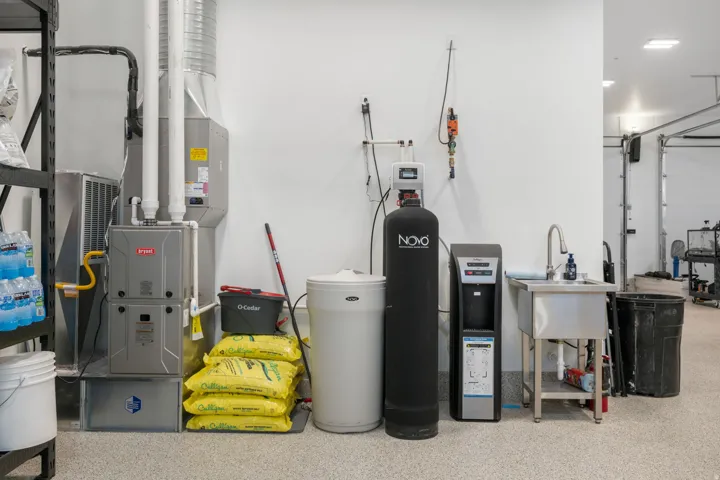 Utility area featuring a furnace system, water softener, water dispenser, and a stainless steel utility sink