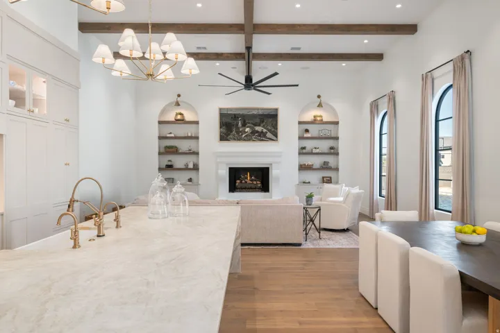 Spacious living area featuring high vaulted ceilings with exposed wood beams, a fireplace with a detailed mantel, and arched windows