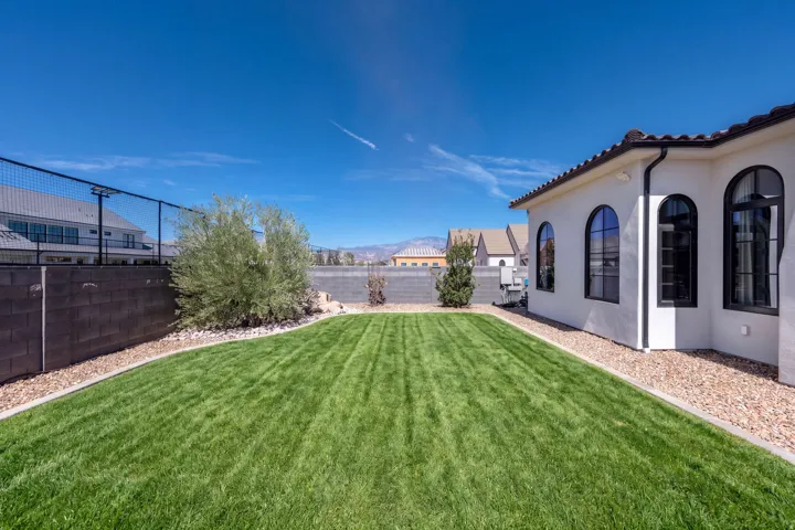 Expansive backyard featuring a manicured lawn, gravel perimeter, and a block retaining wall
