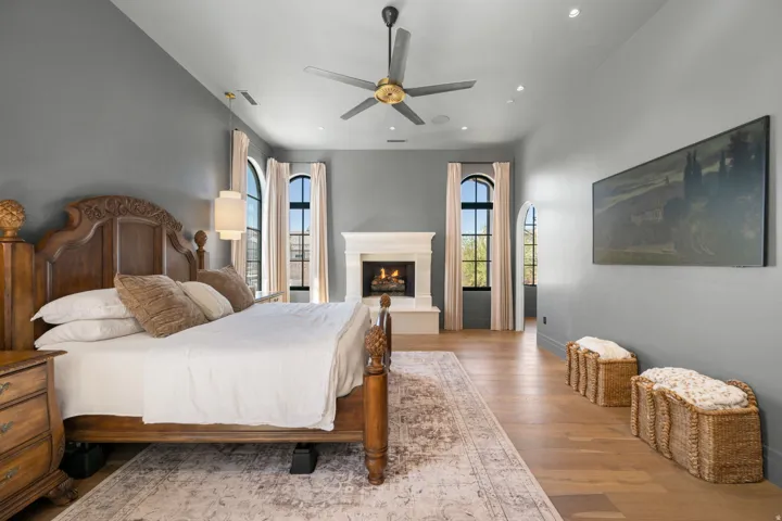 Hardwood flooring, arched windows, and a fireplace with a stone mantel