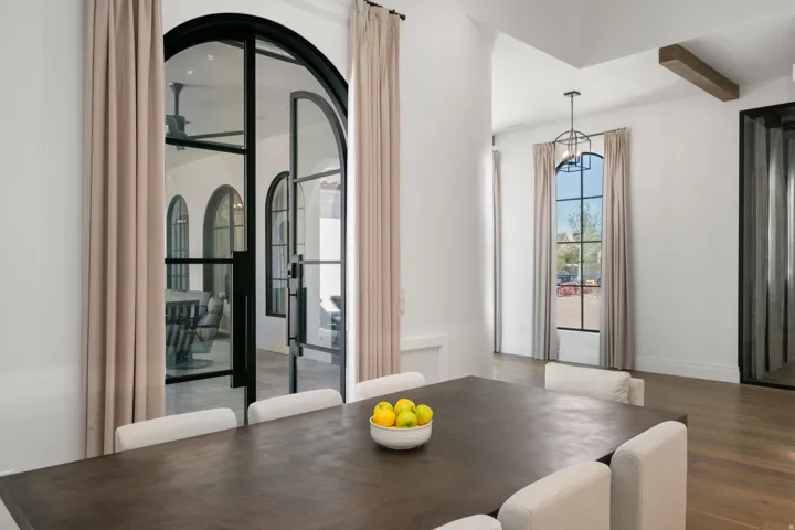 Arched steel-frame glass doors, wood-finish flooring, recessed lighting, exposed ceiling beam, and contemporary pendant light fixture