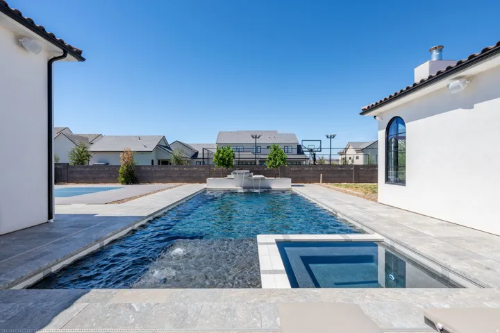 Courtyard-style backyard featuring a swimming pool, integrated spa, and a multi-level water feature