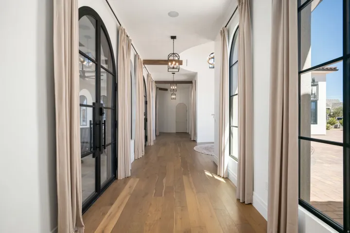 Arched iron-framed doors, wood-finish flooring, recessed lighting, and exposed wood beam accents