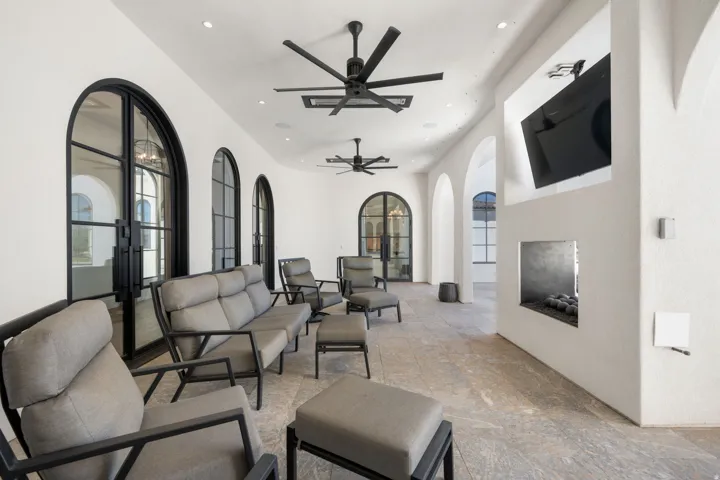Arched iron-framed doors and windows, recessed lighting, ceiling fans, built-in fireplace, and stone-finish flooring