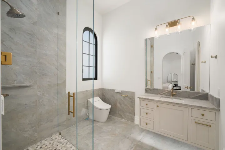 Glass-enclosed shower with a mosaic tile floor and a rainfall showerhead