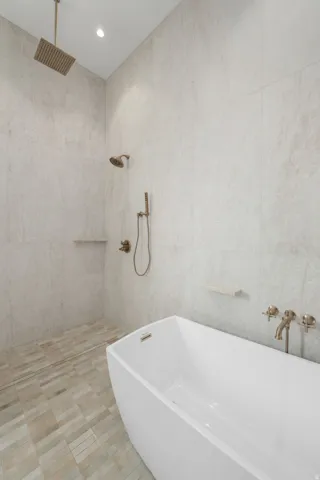 Freestanding soaking tub with wall-mounted bronze-finish faucet