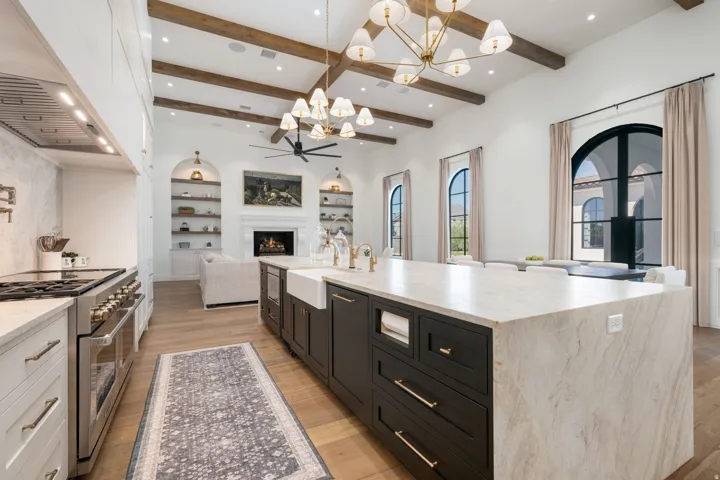 Kitchen featuring a large central island with a farmhouse sink, stainless steel range, and wood-finish flooring