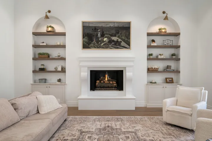 Central fireplace with a substantial mantel, flanked by built-in arched display shelving and lower cabinetry