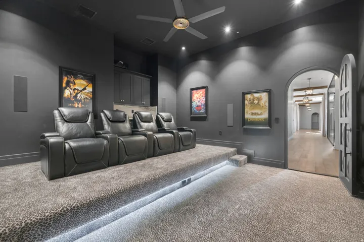 Dedicated home theater featuring tiered seating with individual recliners, ambient ceiling lighting, and LED accent lighting along the floor