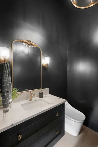 Black vanity with gold-tone hardware, rectangular undermount sink, and light-toned countertop