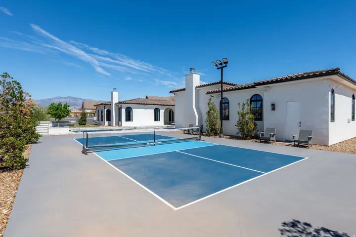 Exterior showcasing a private pickleball court, stucco finish, arched windows, and a tile roof