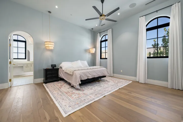 Wood-finish flooring, arched windows, built-in ceiling fan, recessed lighting, and arched doorway