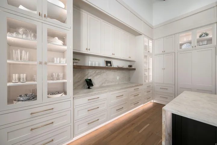 Extensive white cabinetry with varied storage options, including glass-front upper cabinets with interior lighting