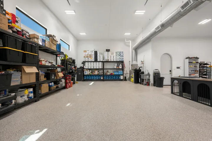Expansive garage with an epoxy floor, high ceilings, recessed lighting, horizontal transom windows, and exposed ductwork