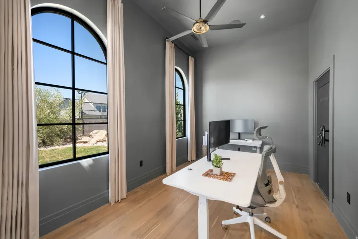 Tall arched windows, wood-finish flooring, ceiling fan, recessed lighting, and a solid door with decorative hardware