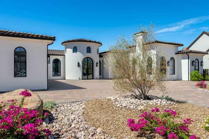 Stucco exterior with a tiled roof, arched windows, and a circular entry tower