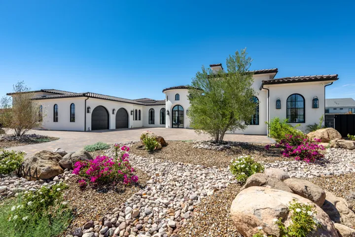 Stucco exterior with arched windows, tile roofing, and a paver driveway
