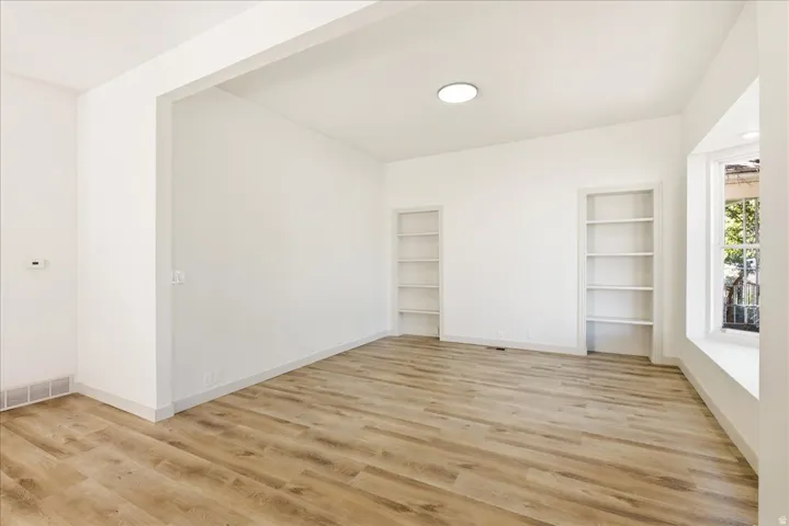 Wood-finish flooring, recessed lighting, built-in shelving, and a bay window with natural light