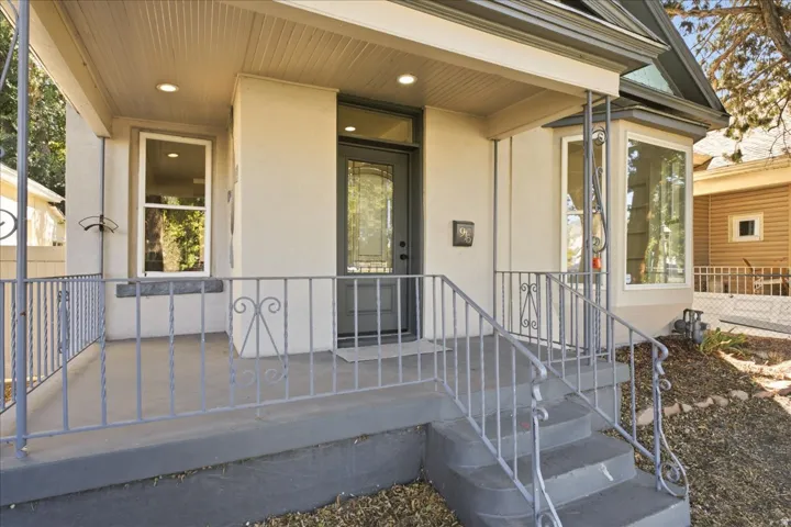 Covered front porch with concrete steps, decorative metal railings, a bay window, and recessed lighting