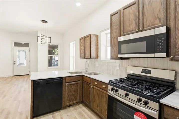 Kitchen featuring wood-finish cabinetry, stainless steel appliances, white countertops, and a tile backsplash