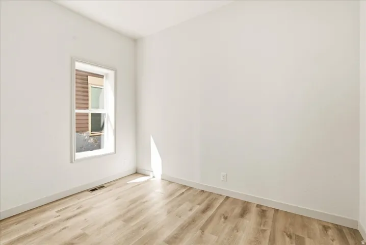 Recessed window with white trim, wood-finish flooring, and light-toned walls