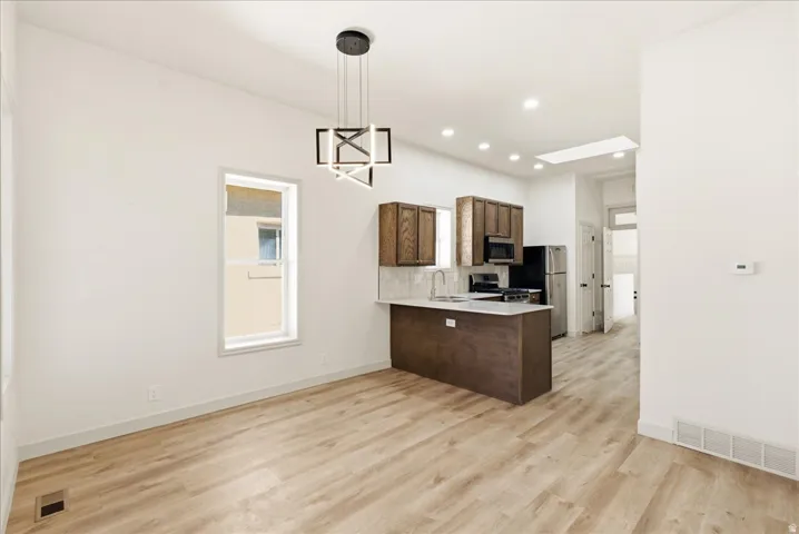 Open-concept living area with wood-finish flooring, a modern linear chandelier, and recessed lighting