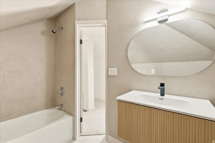 Wood-finish vanity with an integrated sink, matte black faucet, and an illuminated oval mirror