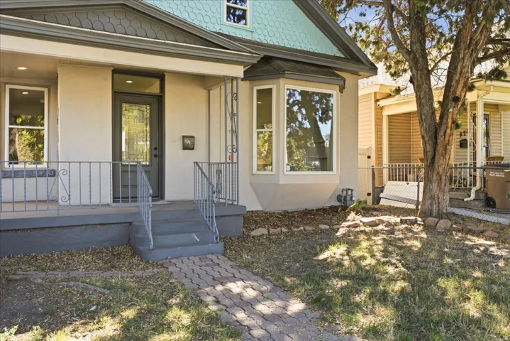 Exterior featuring a covered porch, decorative metal railings, and a front entry door with a glass insert