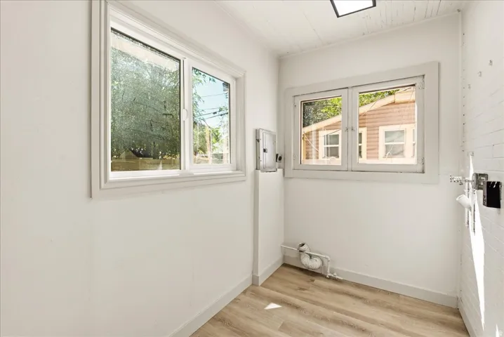 White walls, wood-finish flooring, and white trim windows