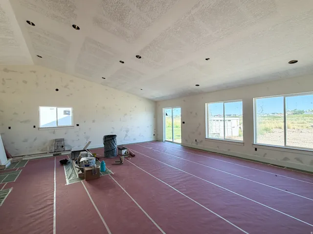 Expansive interior space with vaulted ceilings, recessed lighting, multiple large windows, and a sliding glass door