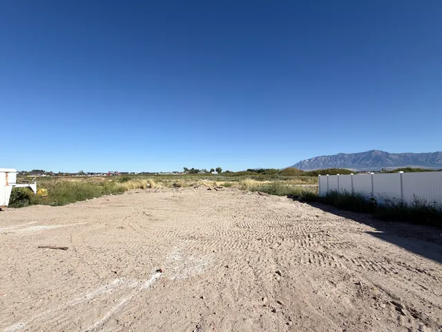 Expansive cleared lot with a white privacy fence and distant mountain range