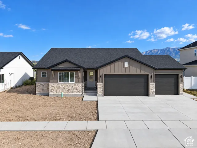 Contemporary exterior featuring stone accents, a dark shingle roof, and a concrete driveway