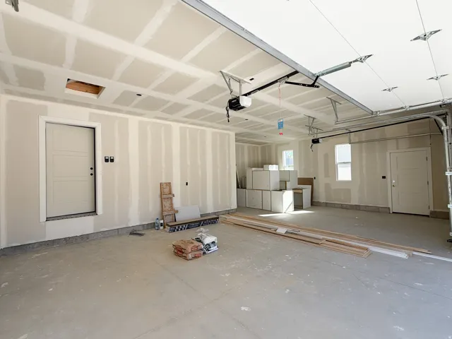 Spacious garage with multiple windows, two entry doors, and an overhead garage door