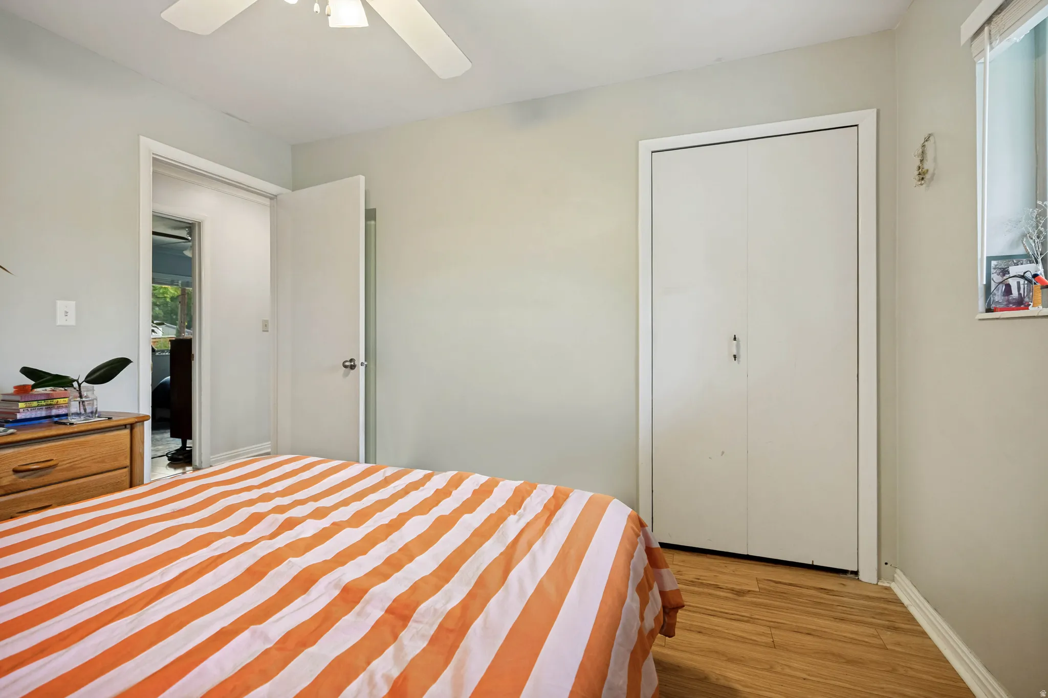 Wood-finish flooring, ceiling fan, white bi-fold closet doors, and recessed window