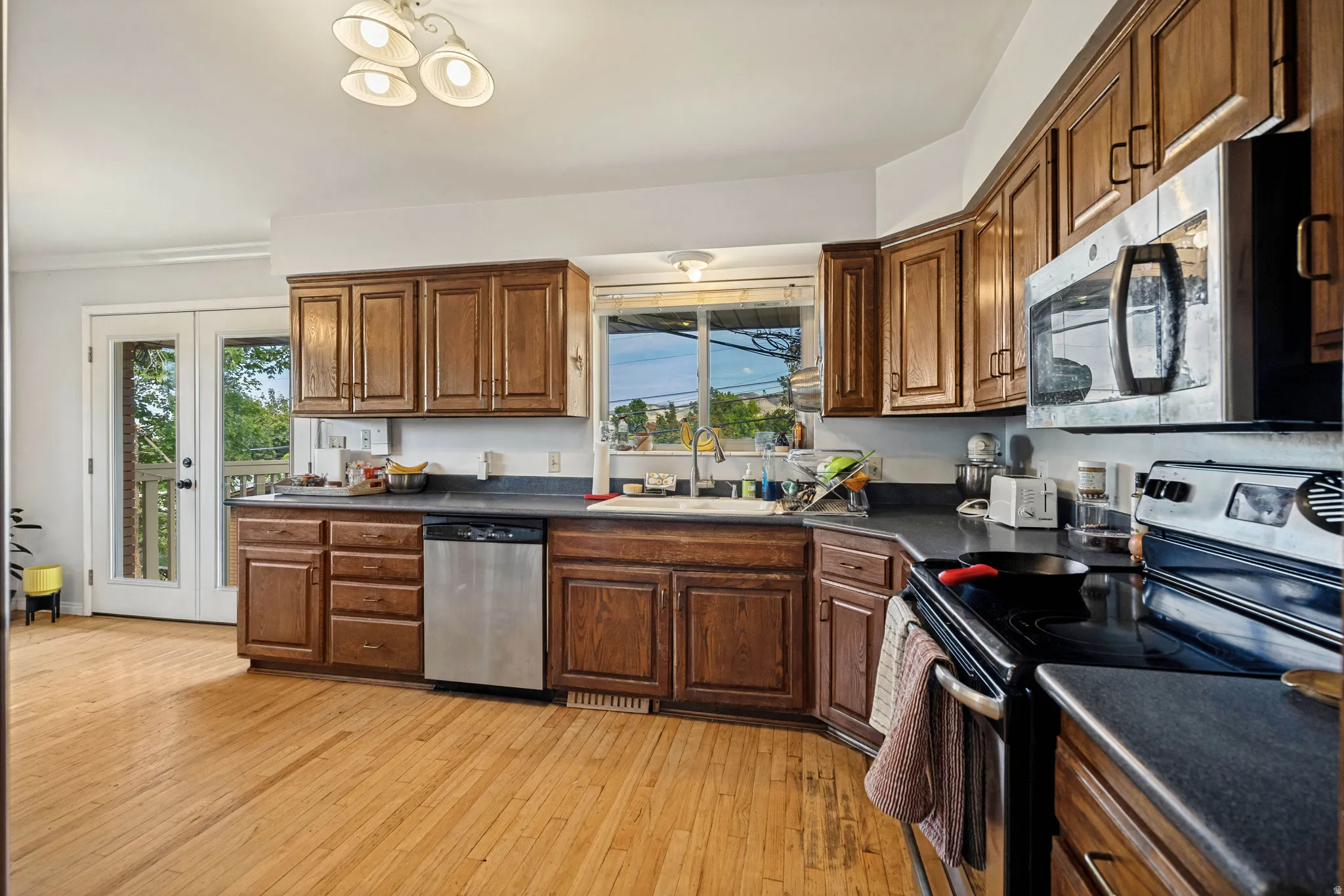 Wood-finish flooring, wood cabinetry, stainless steel dishwasher, stainless steel microwave, and French doors